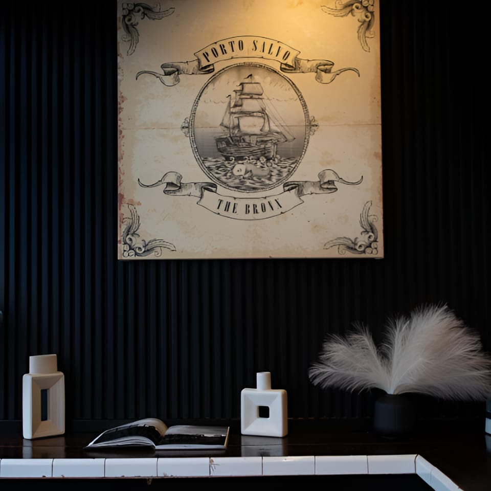 Porto Salvo restaurant's logo, a vintage ship illustration, hangs above decorative vases and an open book.