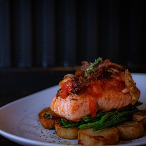 Porto Salvo's salmon dish with tomato salsa, green beans, and roasted potatoes on a white plate.