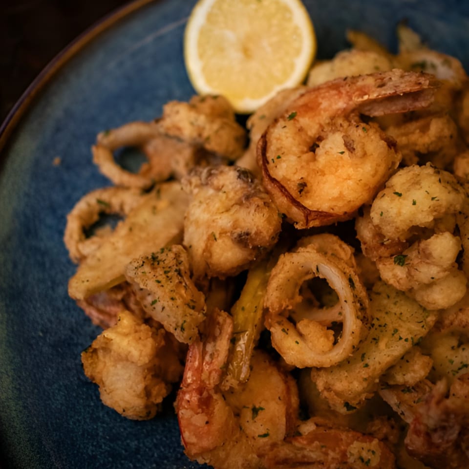 Crispy fried calamari and shrimp with a lemon wedge on a blue plate at Porto Salvo.
