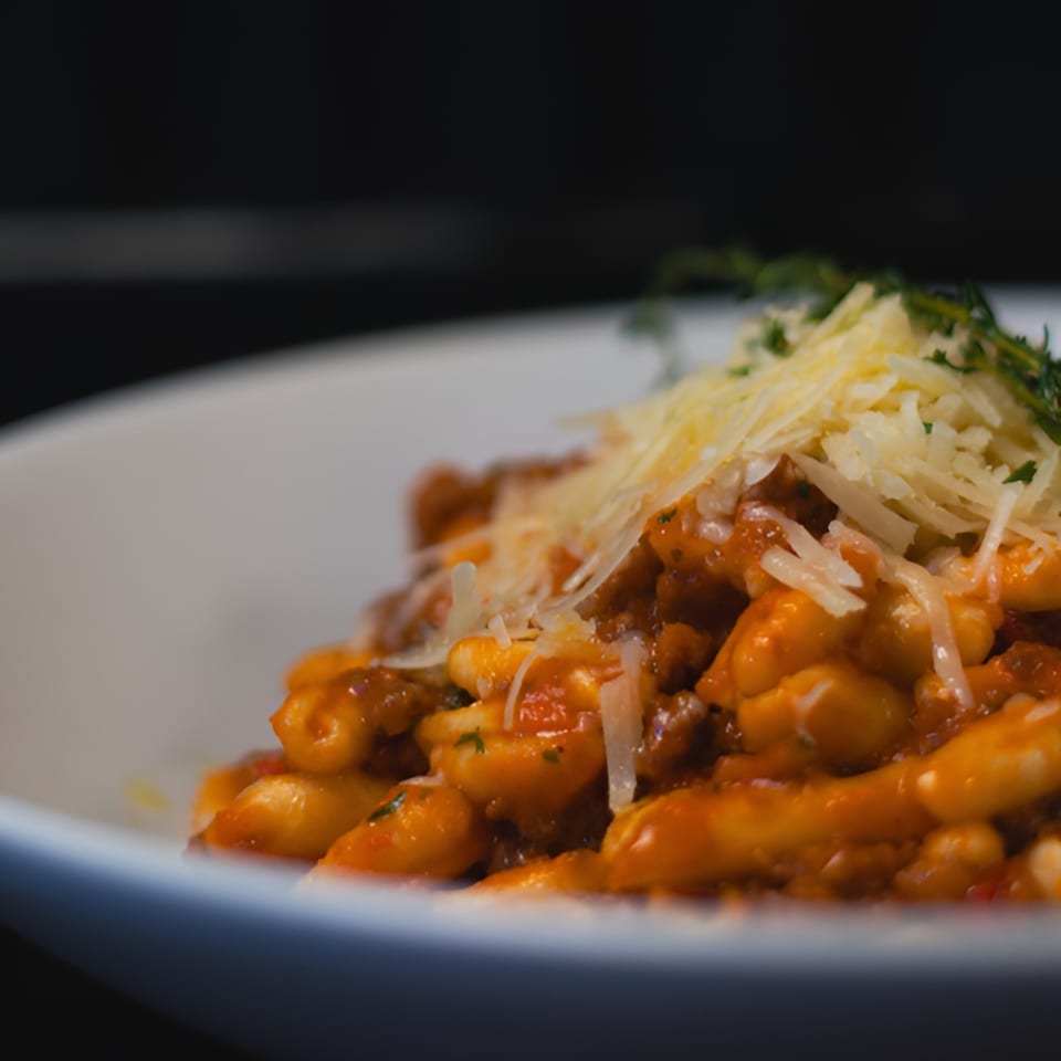 Close-up of Porto Salvo's Italian gnocchi with rich red sauce, parmesan, and fresh herbs.