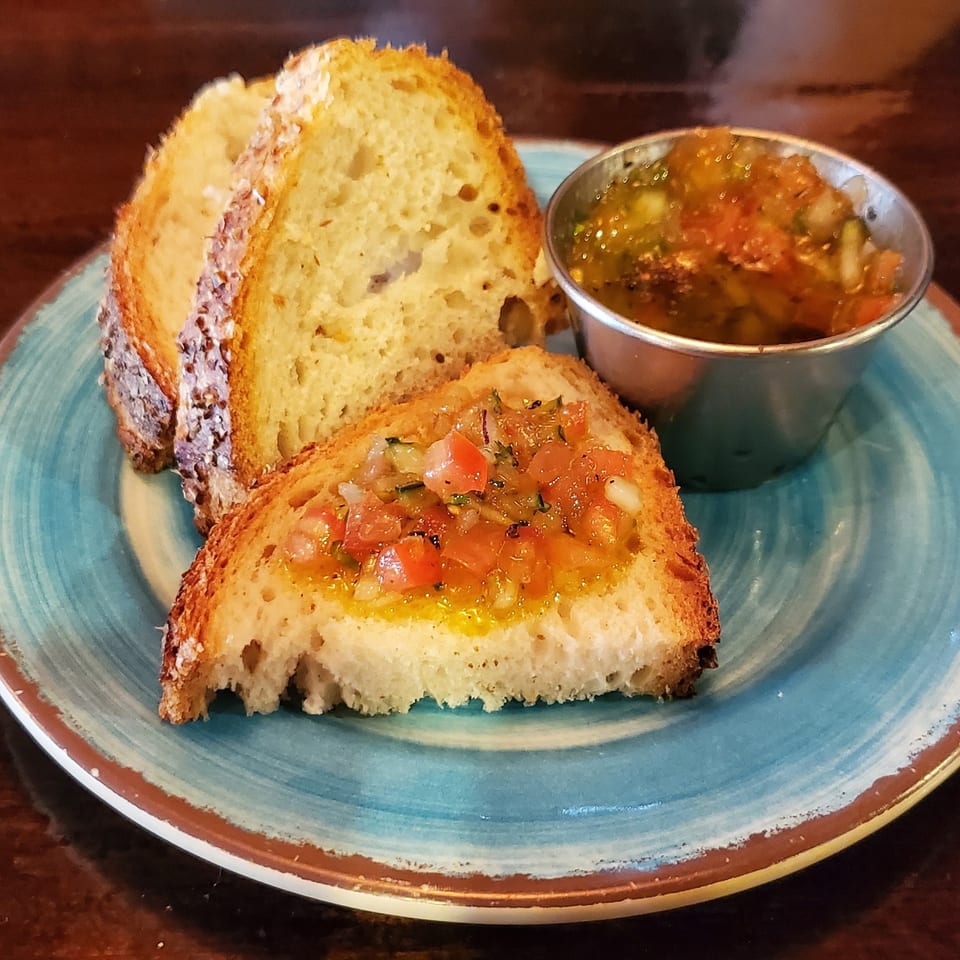 Toasted Italian bread slices with tomato bruschetta topping and a side of olive oil dip.